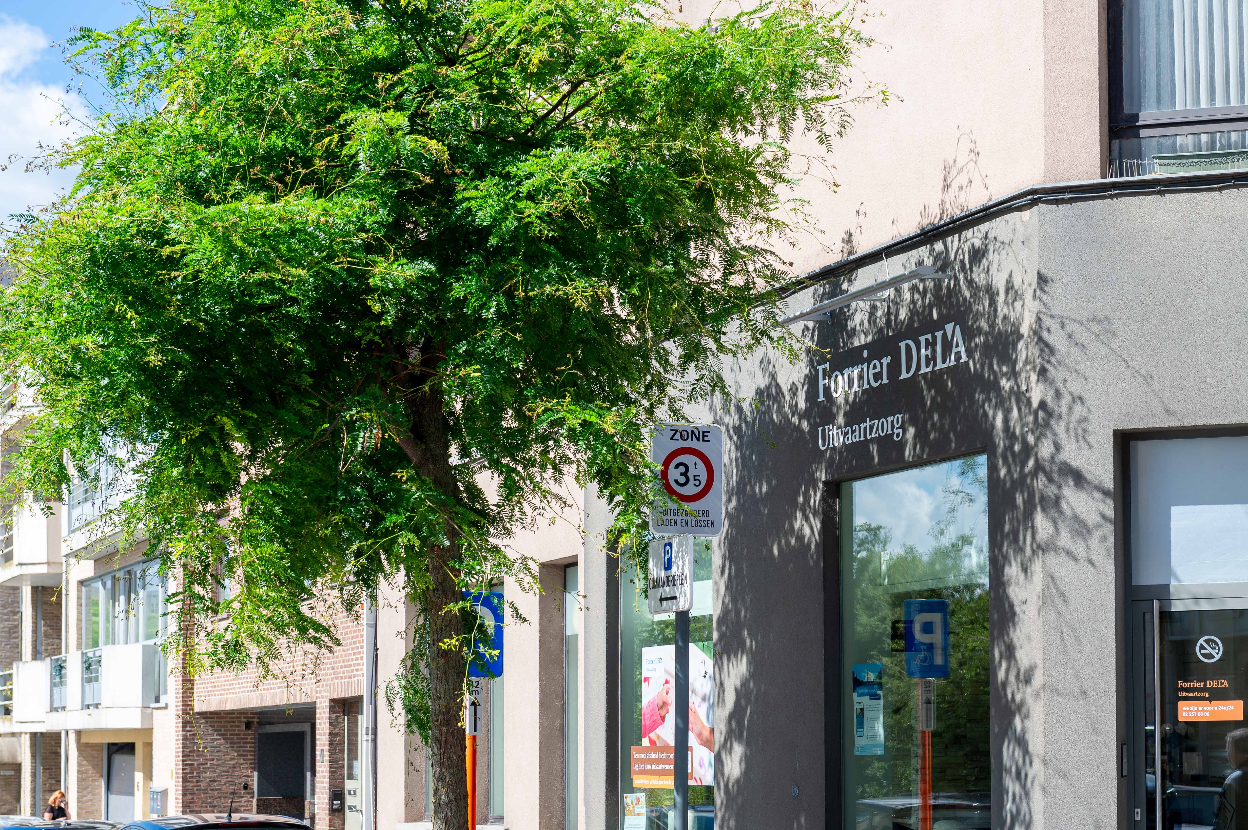 Gevel van Forrier DELA Uitvaartzorg met boom en parkeergelegenheid langs de straat.
